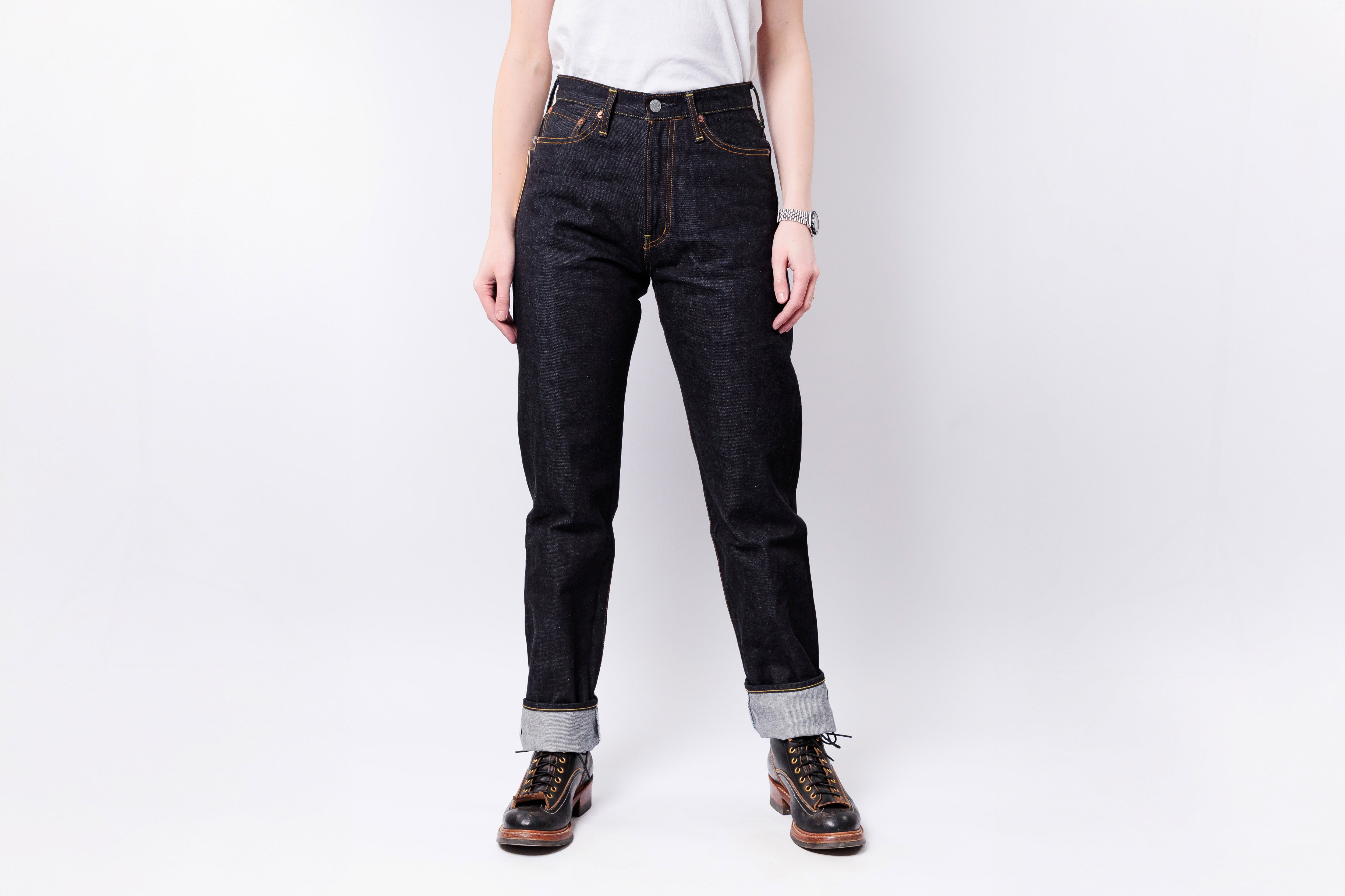 Person wearing dark blue jeans with rolled-up cuffs on a white background