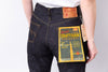 Person wearing dark blue jeans with a visible brand label on a light gray background