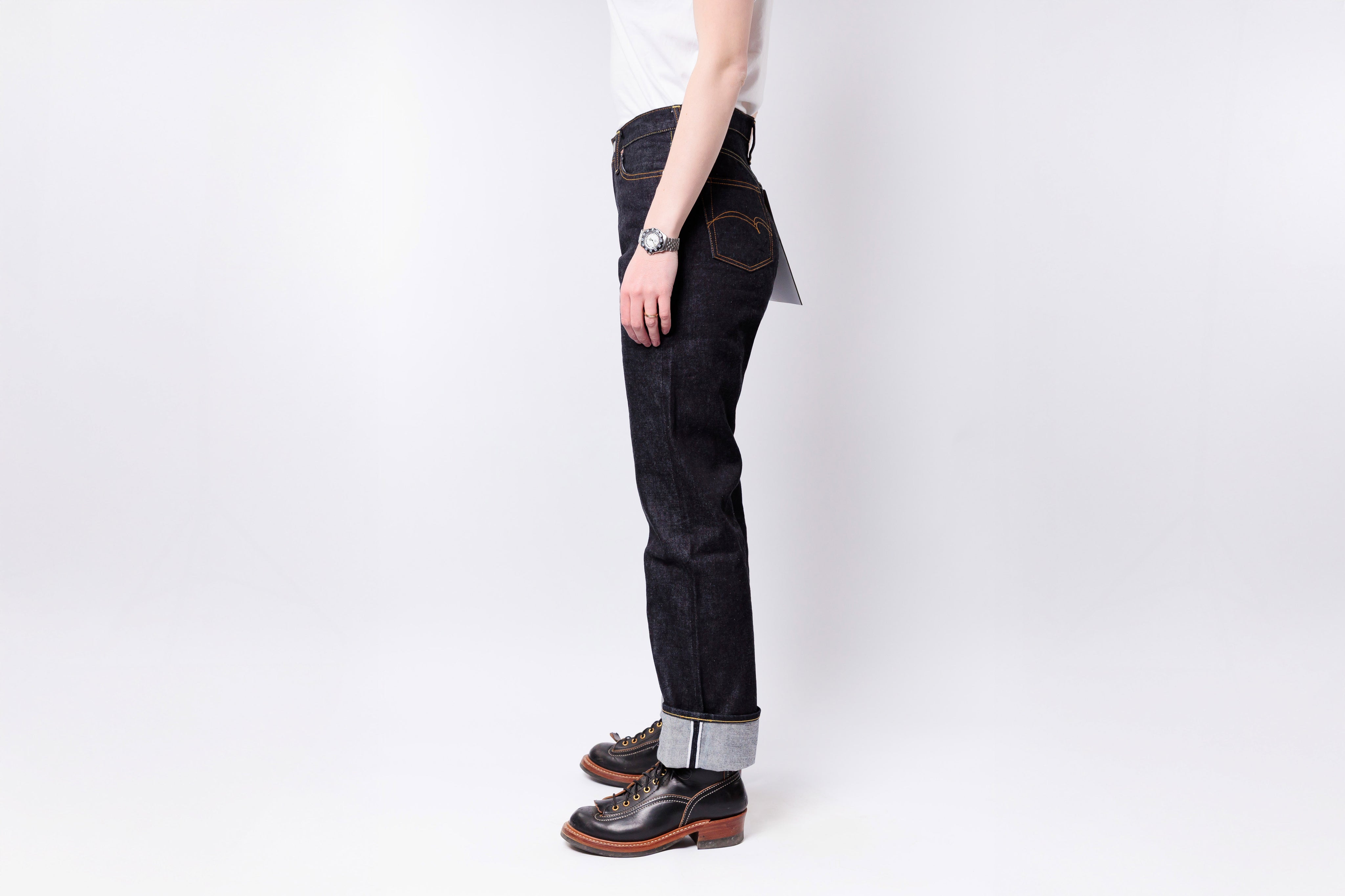 Person wearing black jeans and brown shoes on a white background