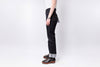 Person wearing black jeans and brown shoes on a white background