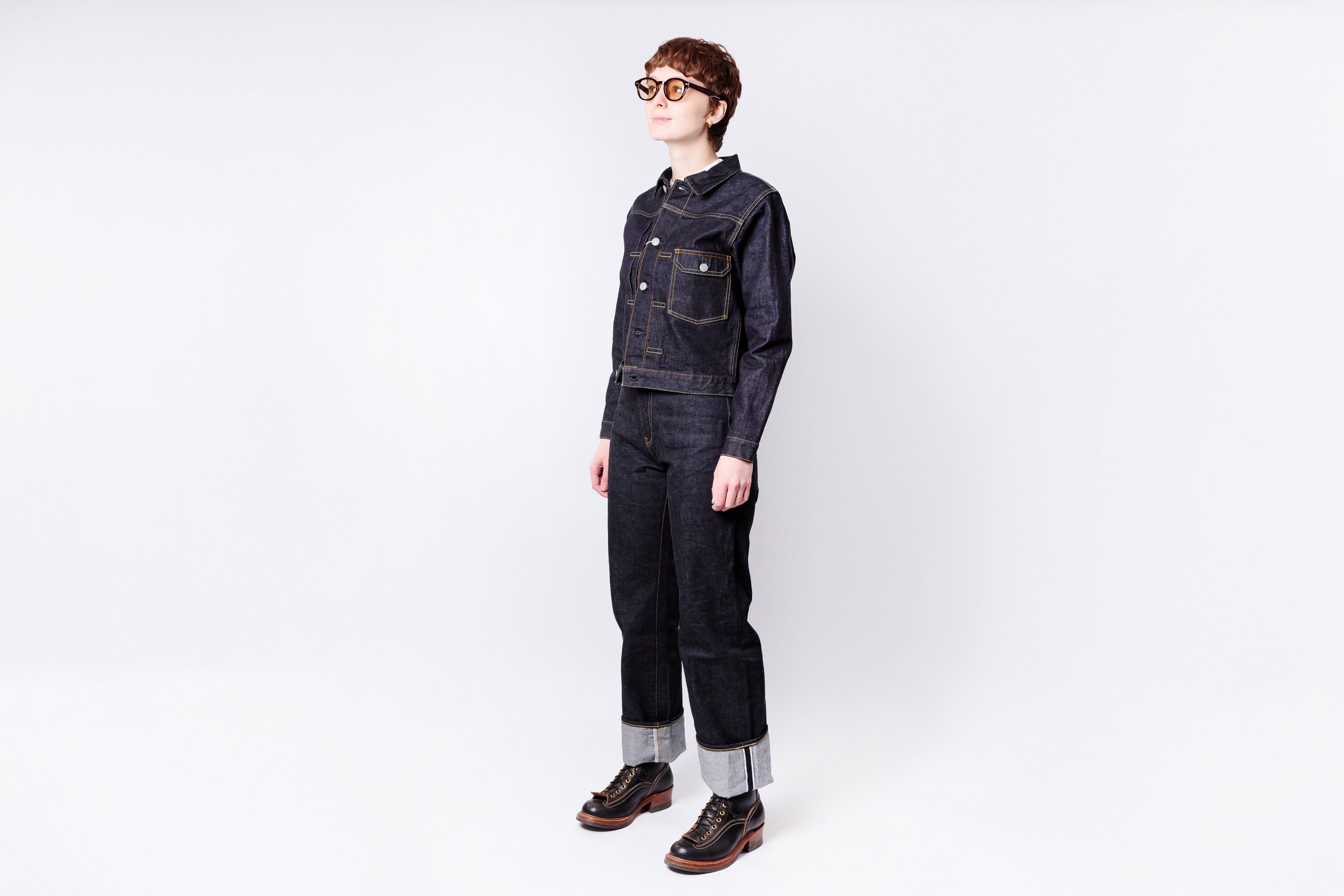 Person wearing a dark denim outfit on a white background