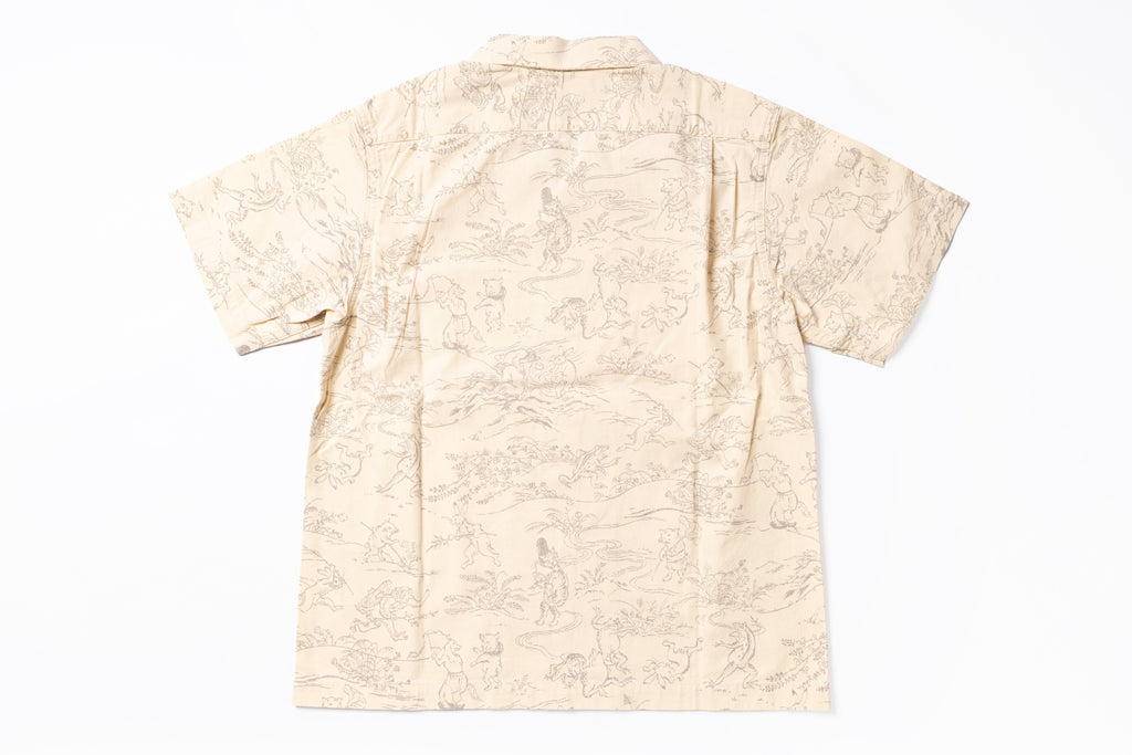 A short-sleeve camp collar shirt in beige with a light brown scenic toile-style print, shown flat against a white background.