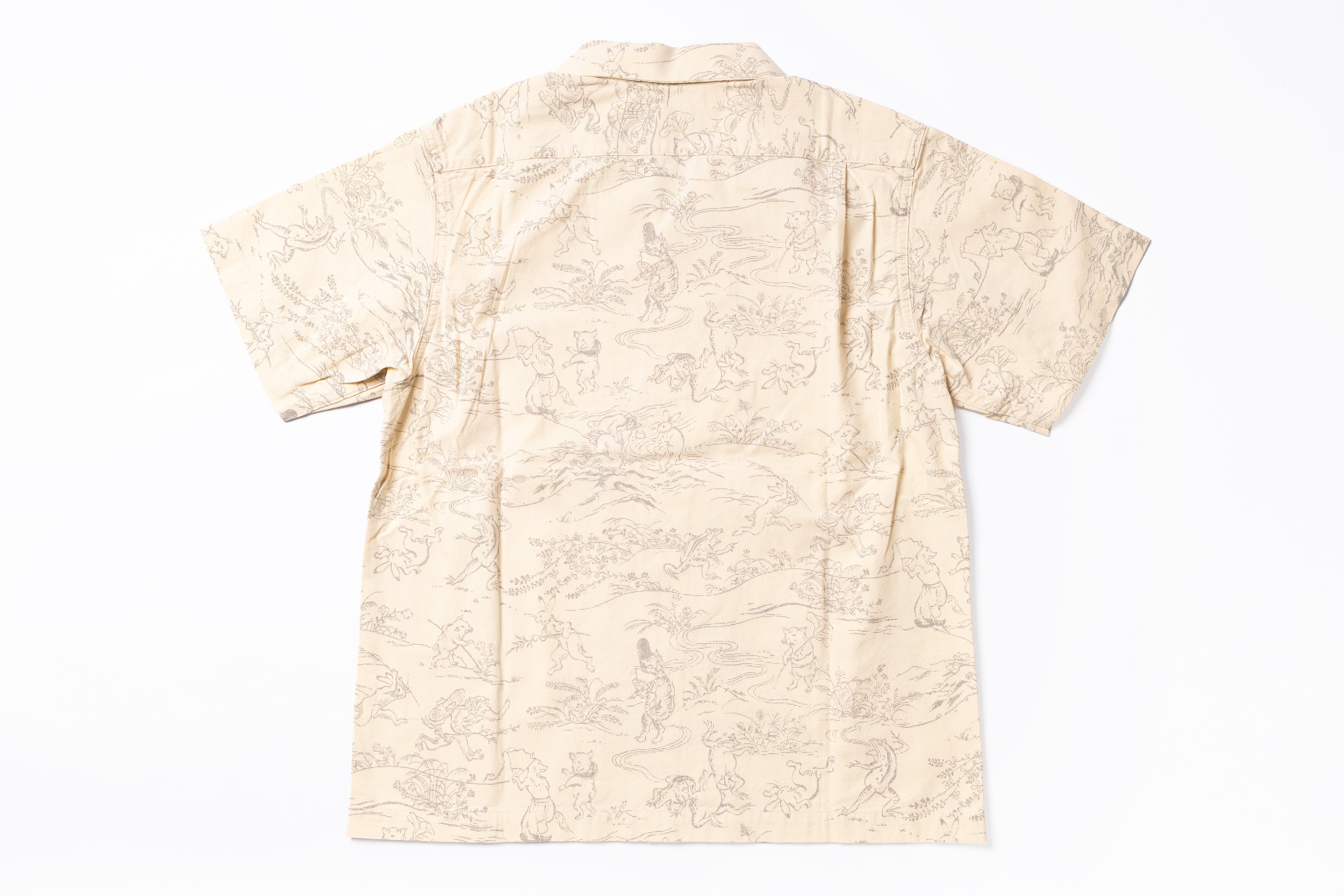 A short-sleeve camp collar shirt in beige with a light brown scenic toile-style print, shown flat against a white background.