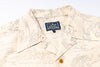 Close-up of a cream-colored short-sleeve button-up shirt with a fine gray line-art print and a visible Studio Darliau neck label.