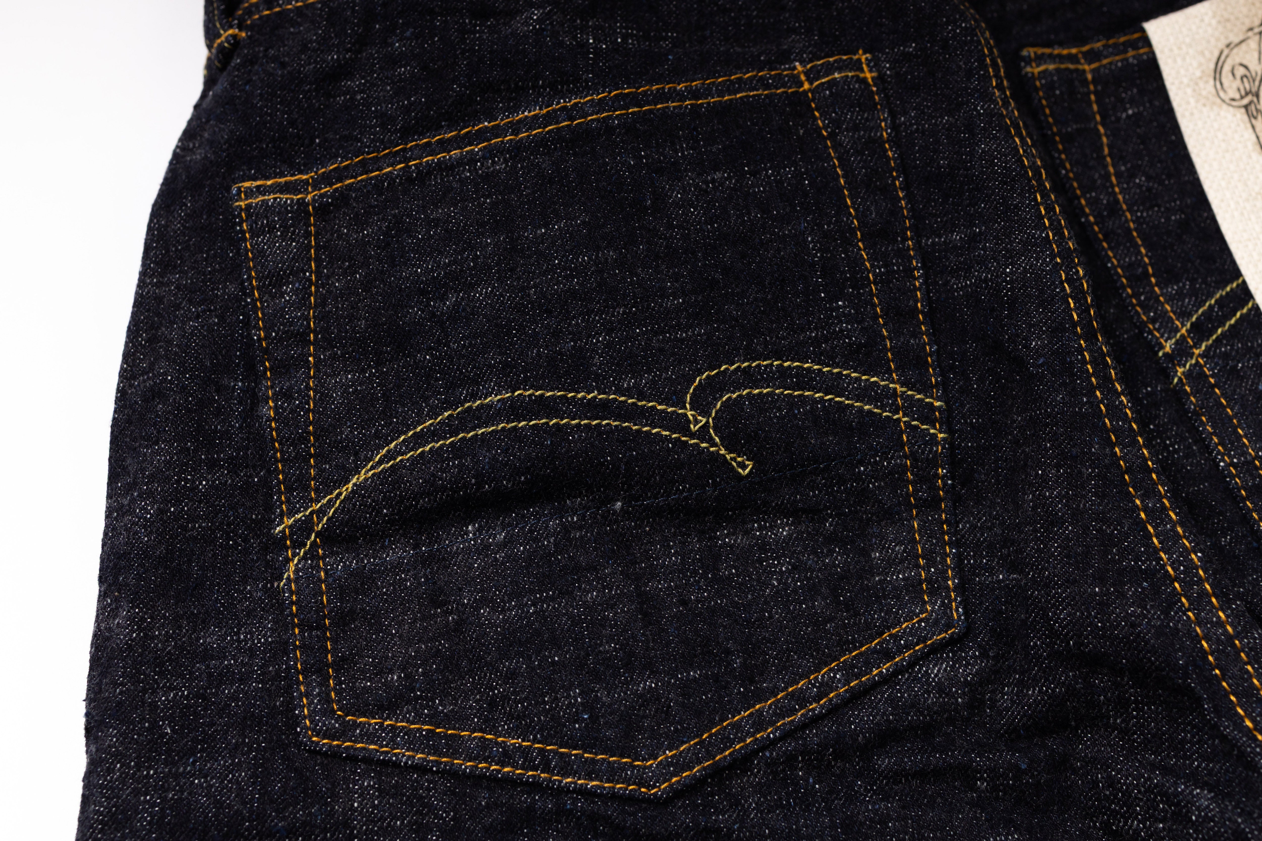 Close-up of a dark blue denim pocket with yellow stitching on a white background