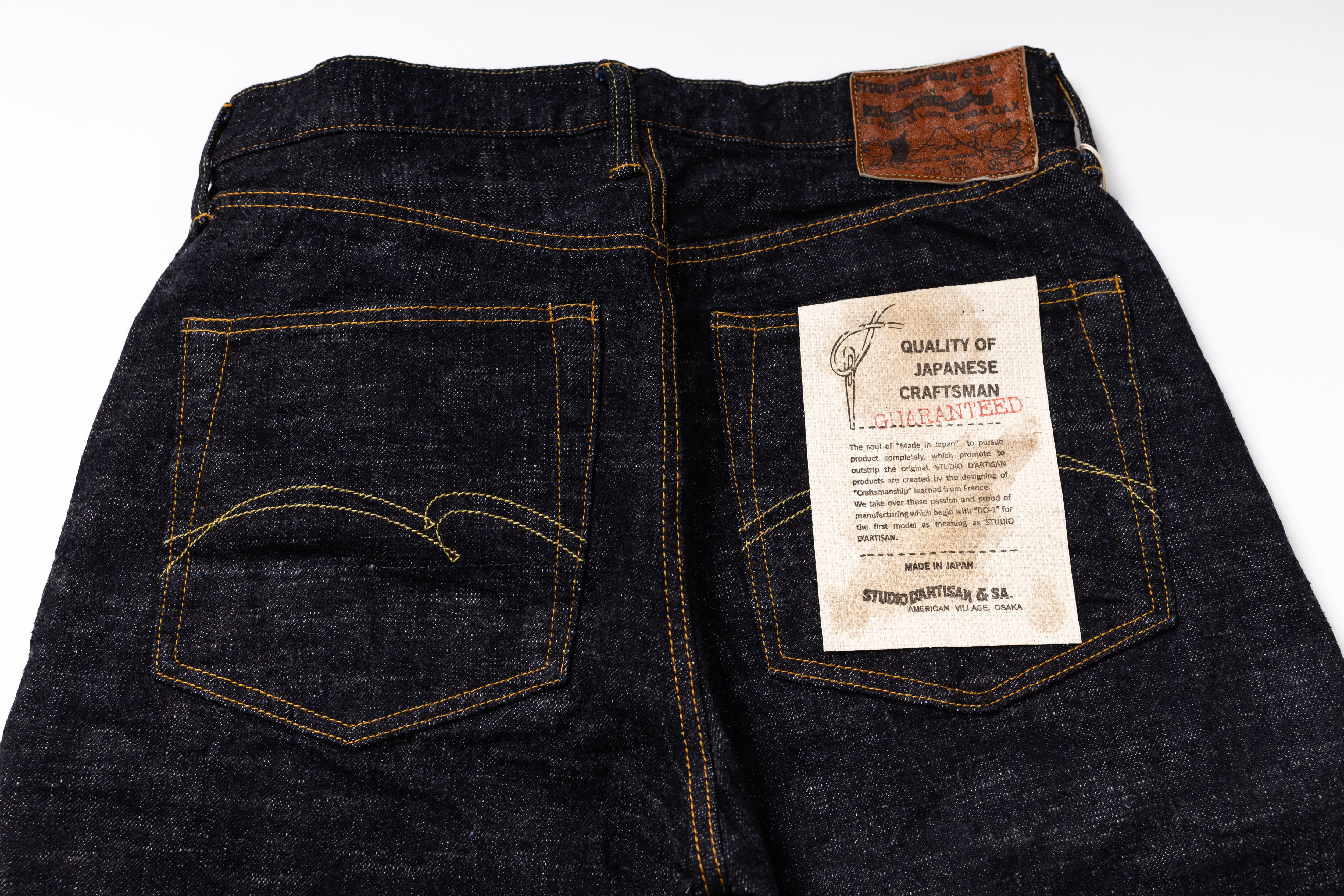 Dark blue denim jeans with a label on a white background