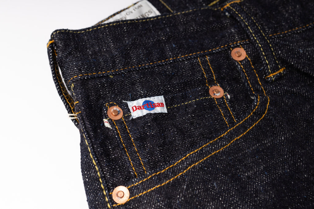Close-up of a dark denim pocket with a brand label on a white background