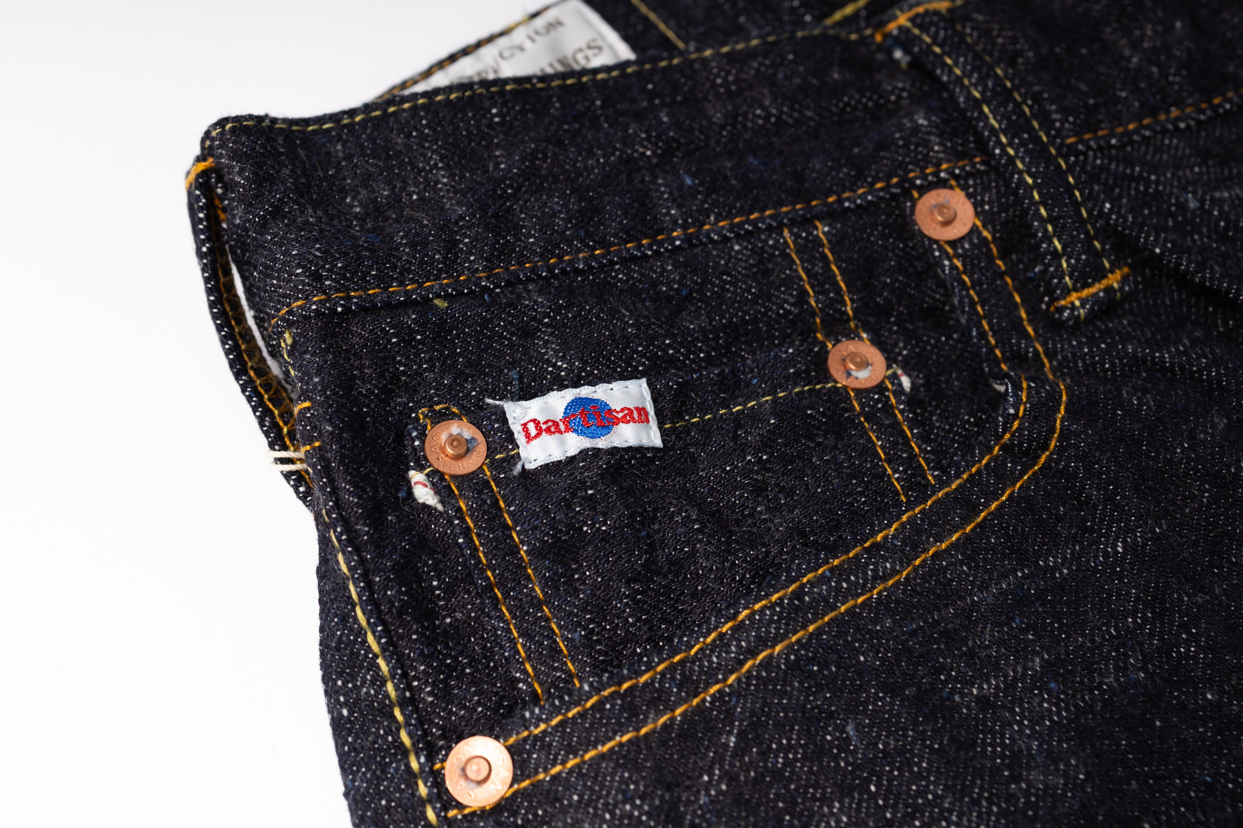 Close-up of a dark denim pocket with a brand label on a white background