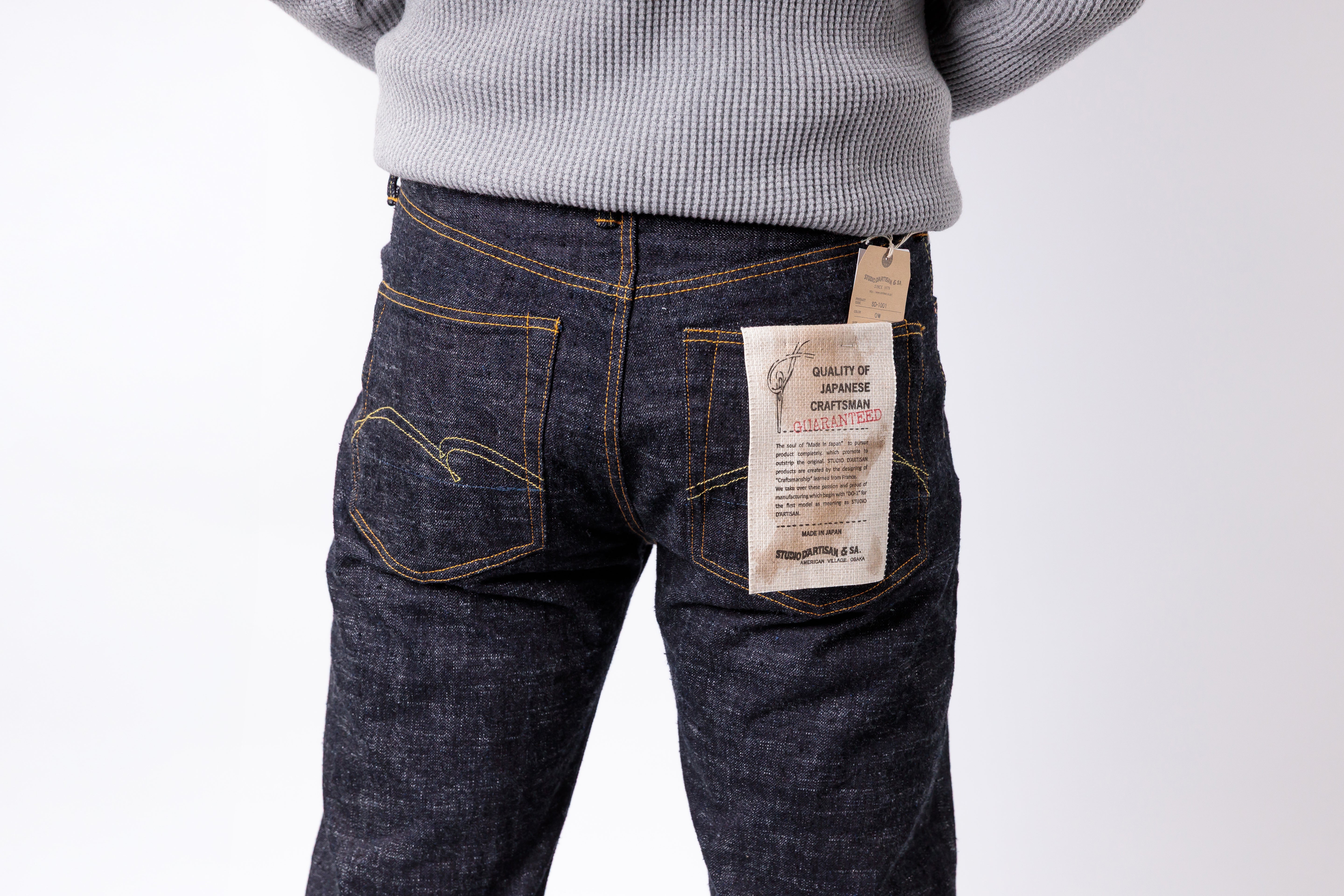Person wearing dark blue jeans with a visible brand label on a white background