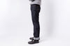 Person wearing dark blue jeans and black shoes on a white background