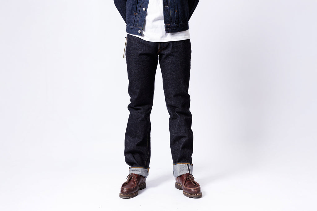 Person wearing dark jeans and a denim jacket on a white background