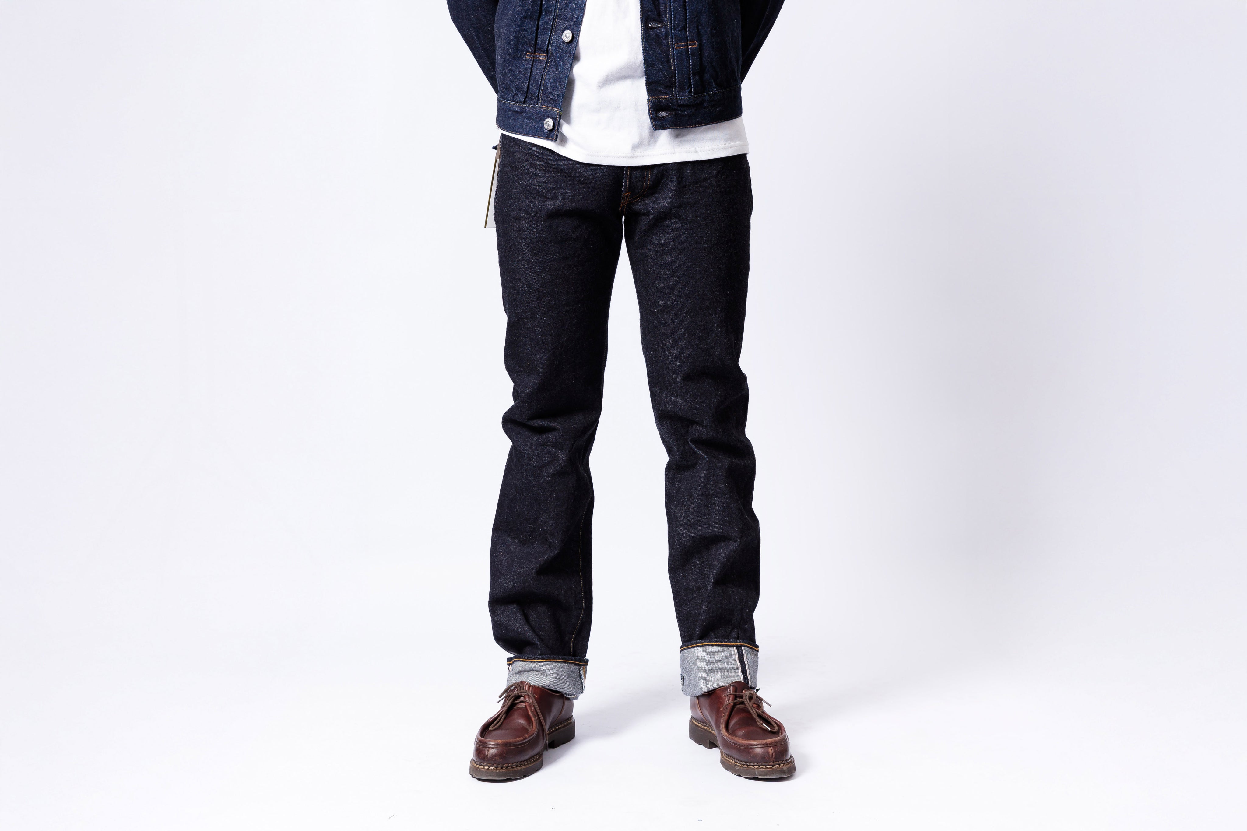 Person wearing dark jeans and a denim jacket on a white background