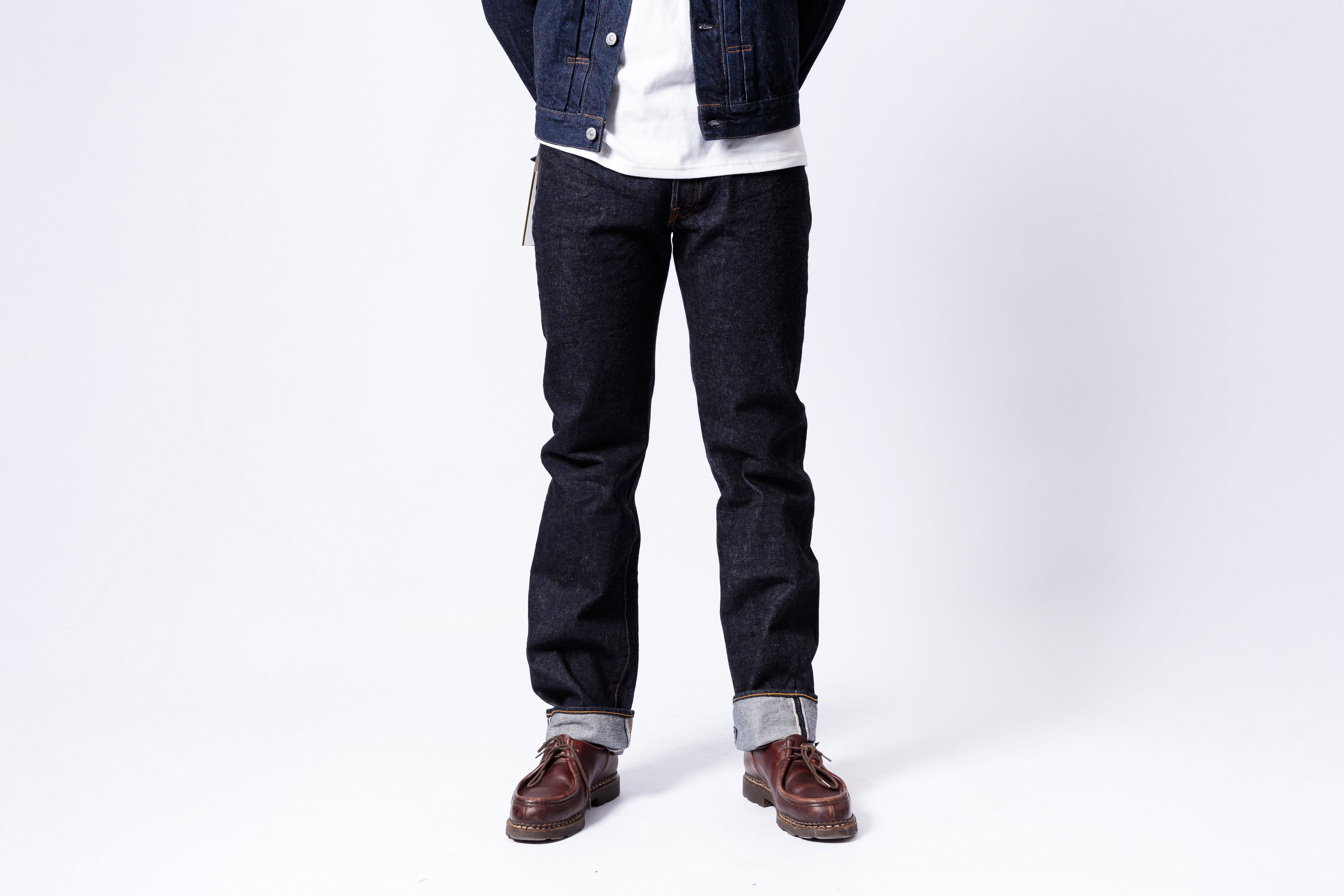 Person wearing dark jeans and a denim jacket on a white background