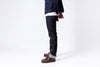 Person wearing dark jeans and brown shoes on a white background