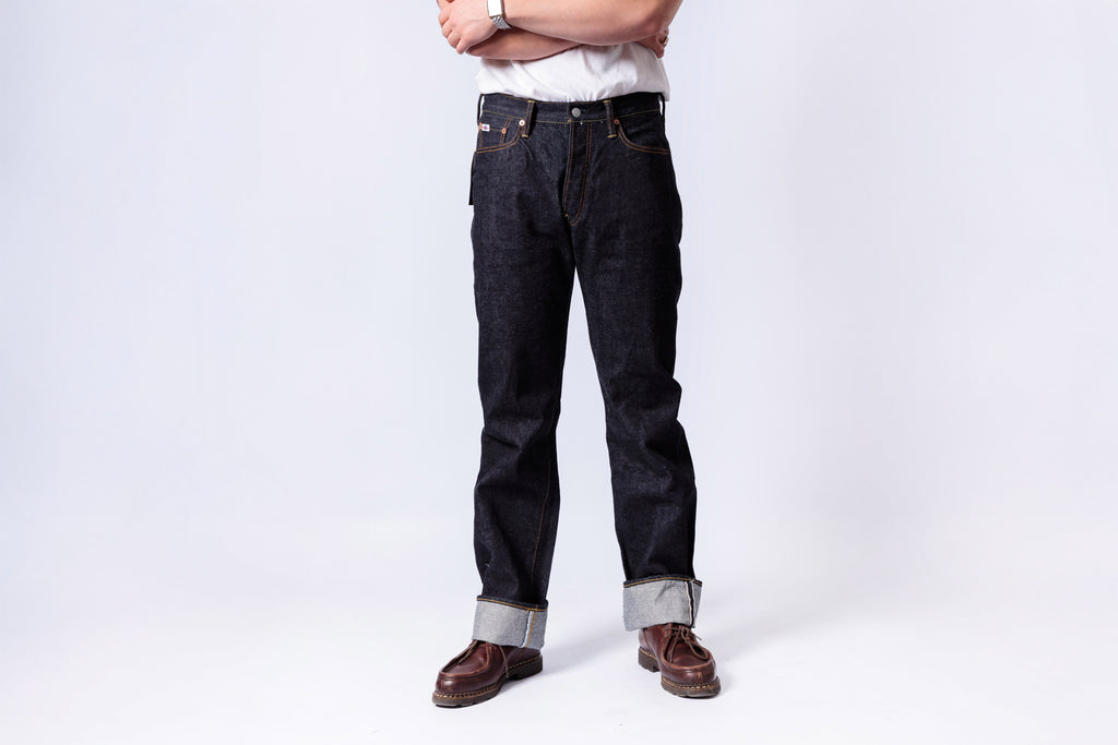 Person wearing dark jeans and brown boots on a white background
