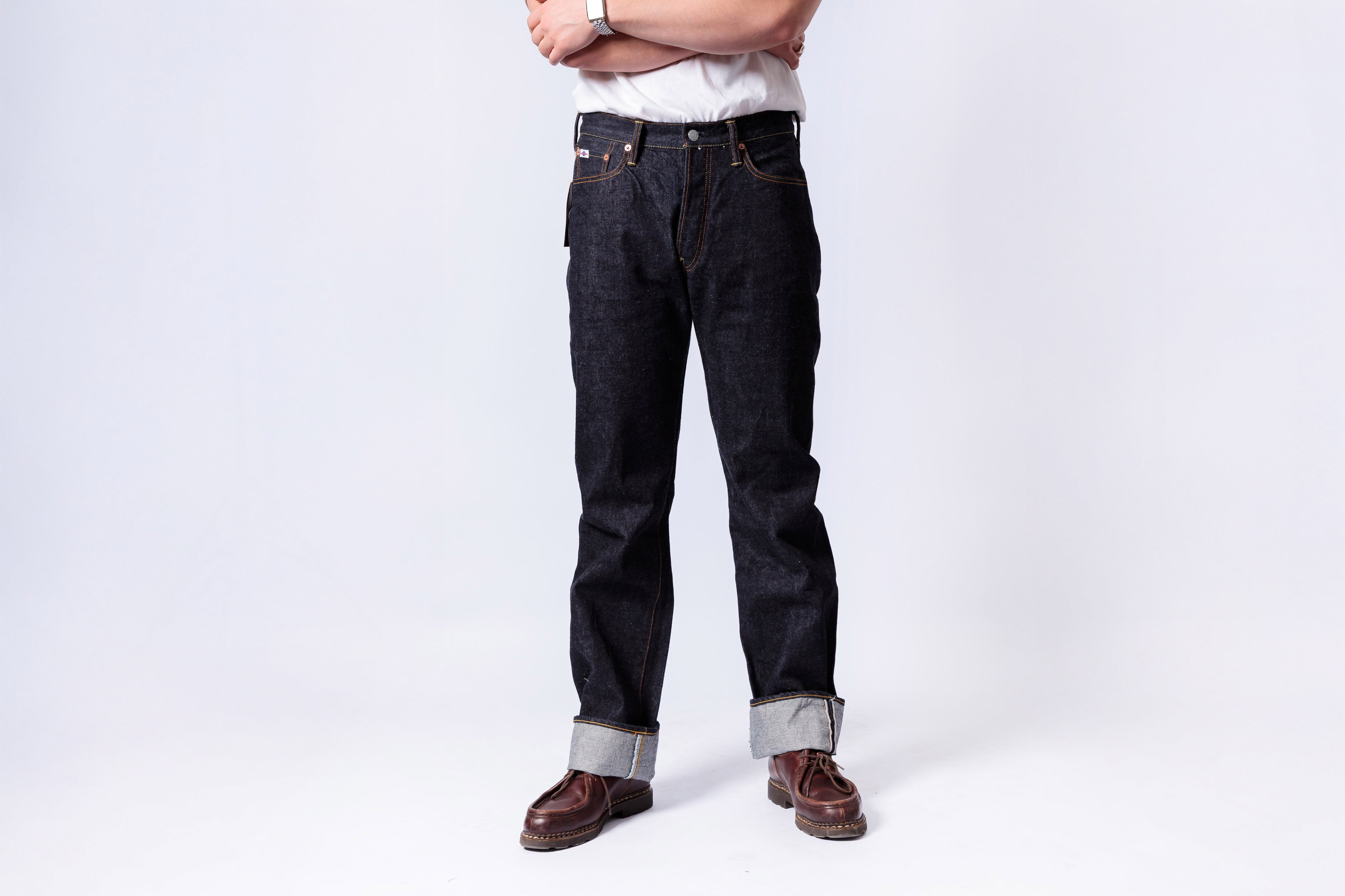 Person wearing dark jeans and brown boots on a white background