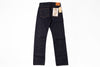 Dark indigo denim jeans shown from the back, featuring a classic five-pocket design, a leather patch at the back waistband, and paper tags attached to the rear pockets, set against a plain white background.