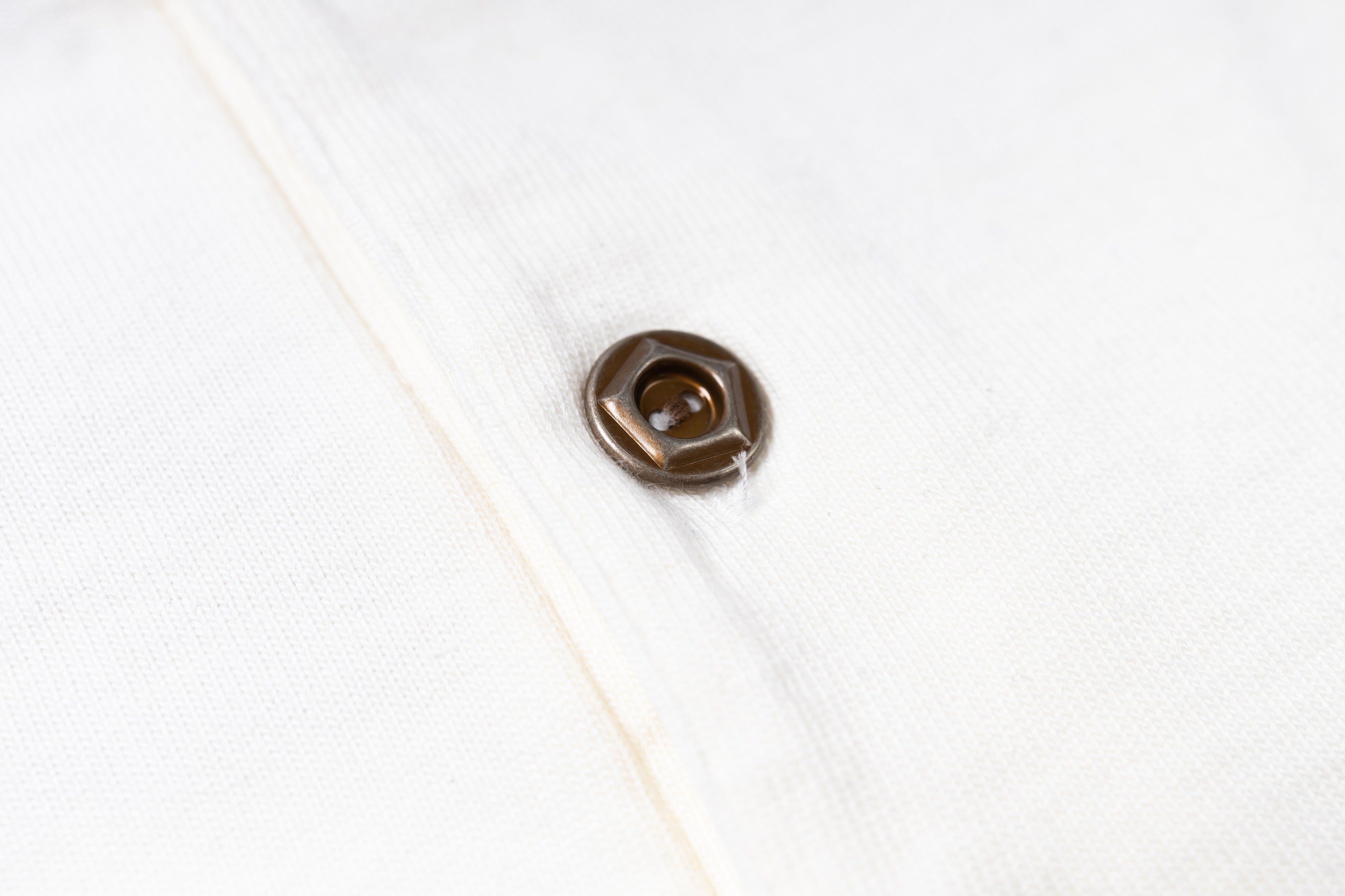 Close-up of a brown button on a white shirt
