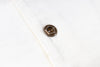 Close-up of a brown button on a white shirt