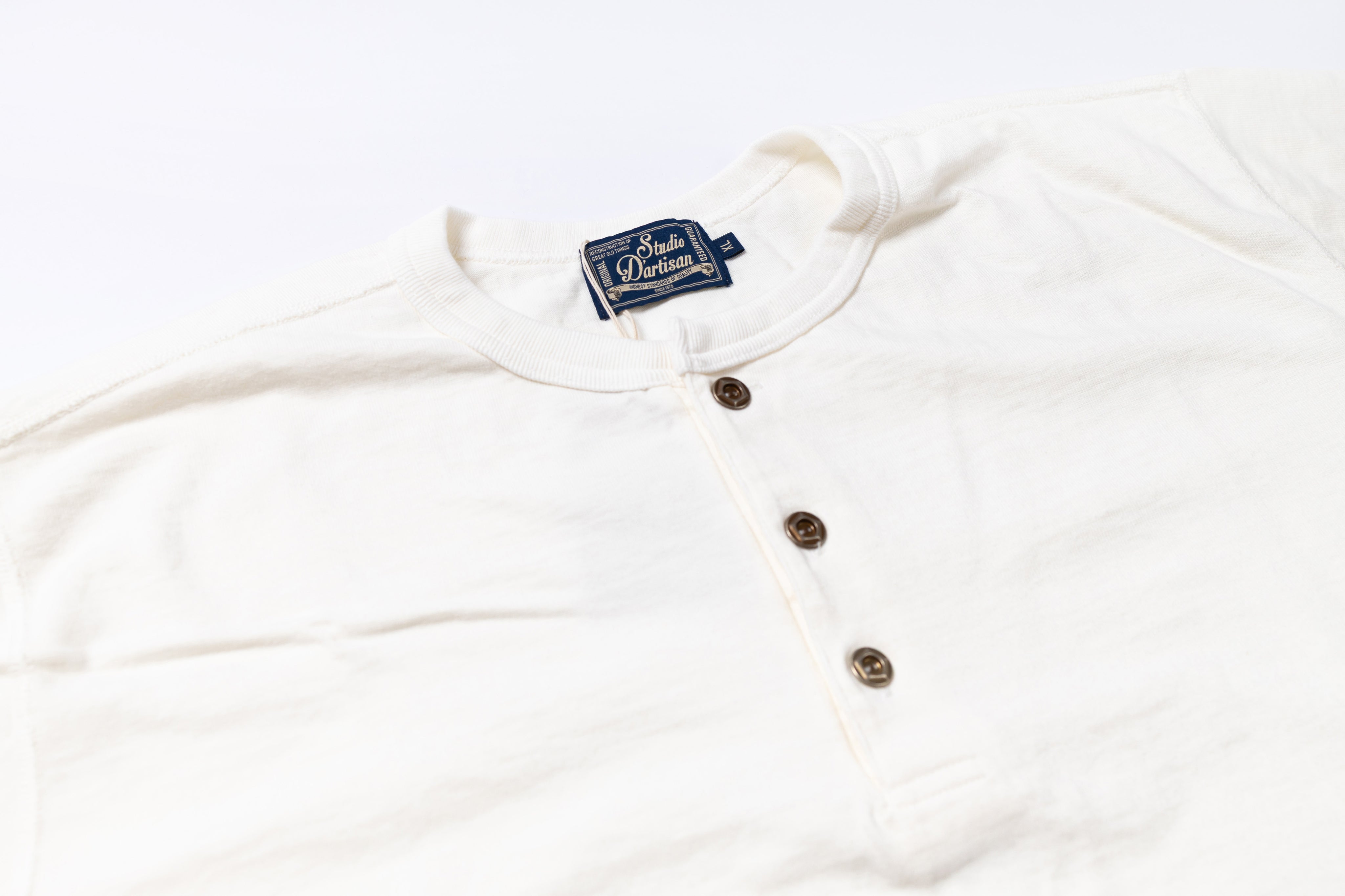 White long-sleeve shirt with buttons and a brand label on a white background
