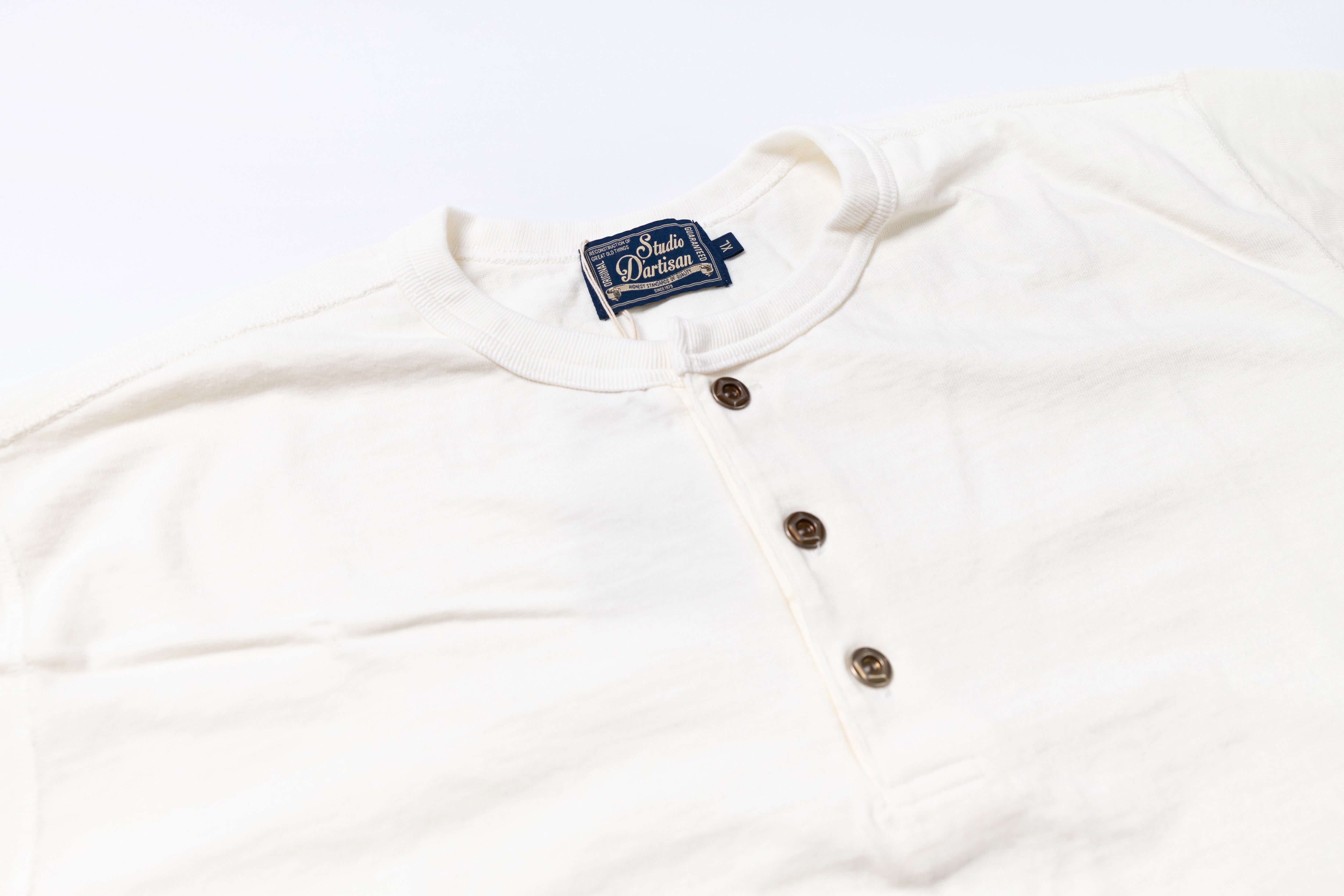 White long-sleeve shirt with buttons and a brand label on a white background