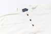 White long-sleeve shirt with buttons and a brand label on a white background