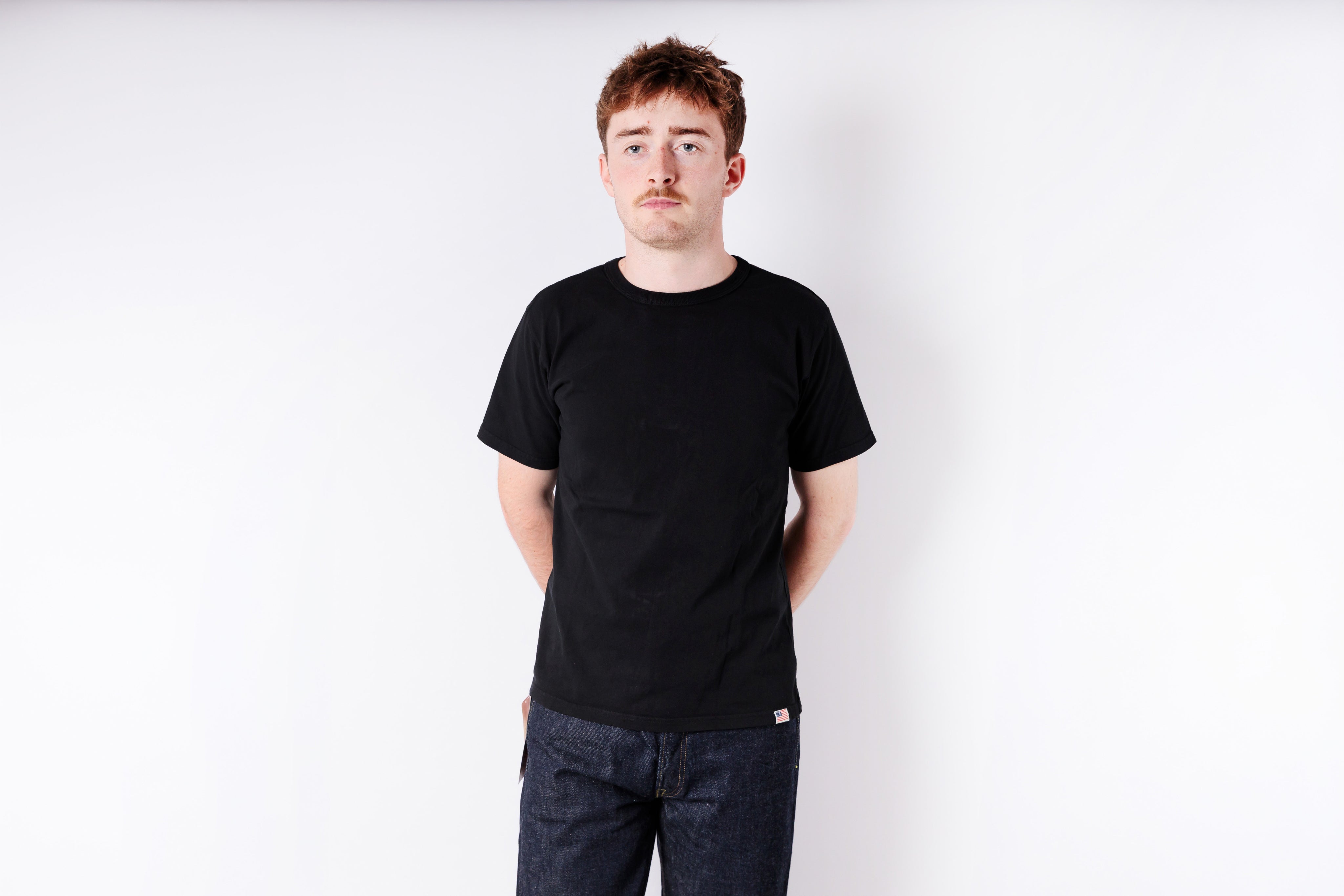 Person wearing a black t-shirt and jeans on a white background