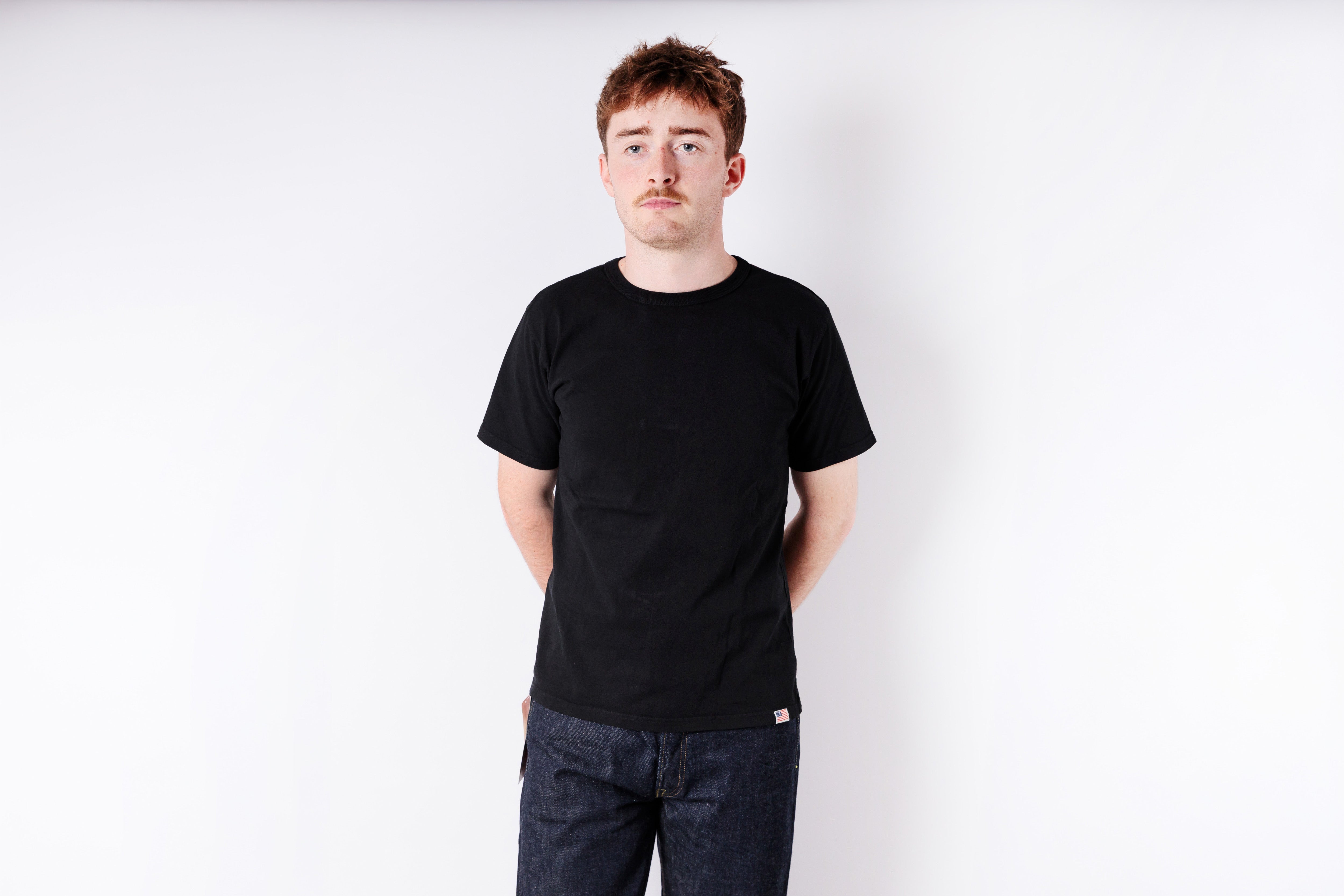 Person wearing a black t-shirt and jeans on a white background