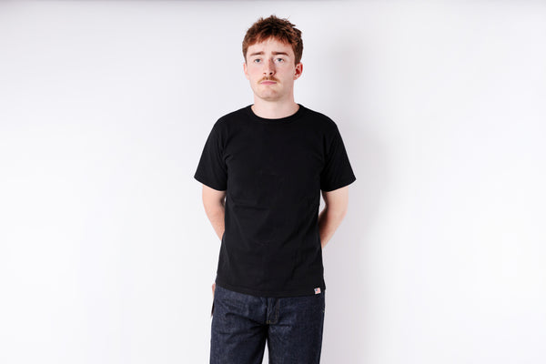 Person wearing a black t-shirt and jeans on a white background
