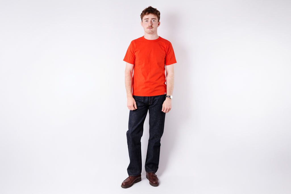 Person wearing a red t-shirt and dark pants on a white background