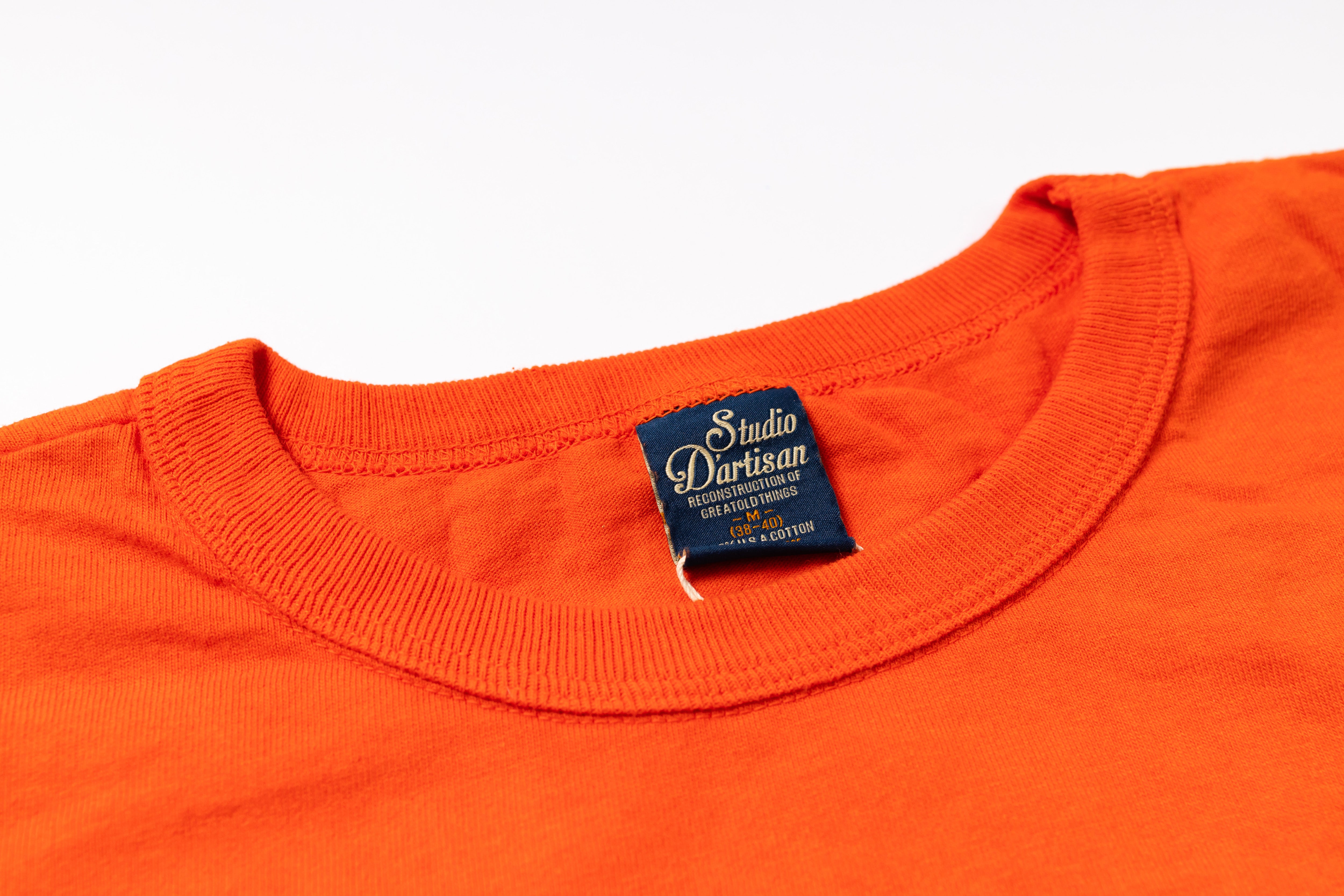 Close-up of an orange shirt with a visible label on a white background