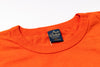 Close-up of an orange shirt with a visible label on a white background