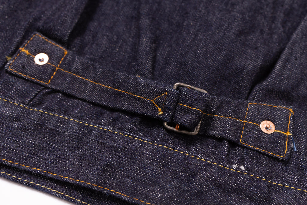 Close-up of a dark blue denim fabric with a belt and button details.