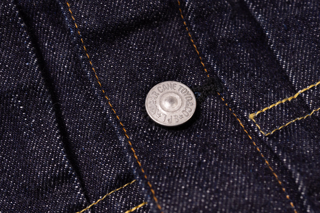 Close-up of a button on dark blue denim fabric with 'Levi's' branding.