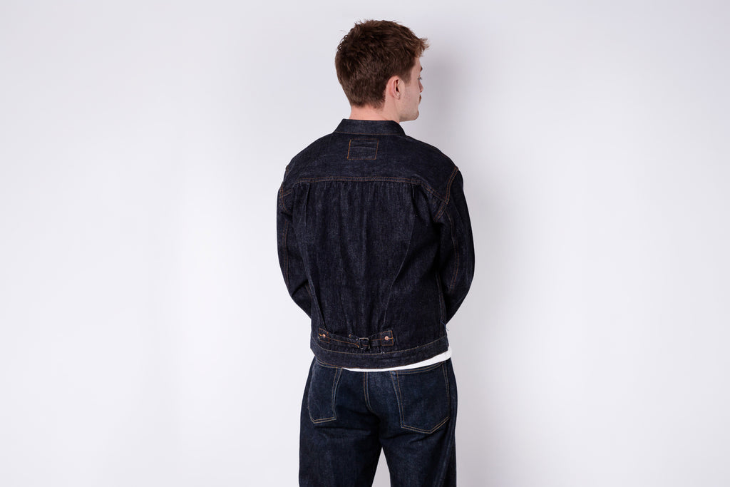 Person wearing a dark denim jacket on a white background