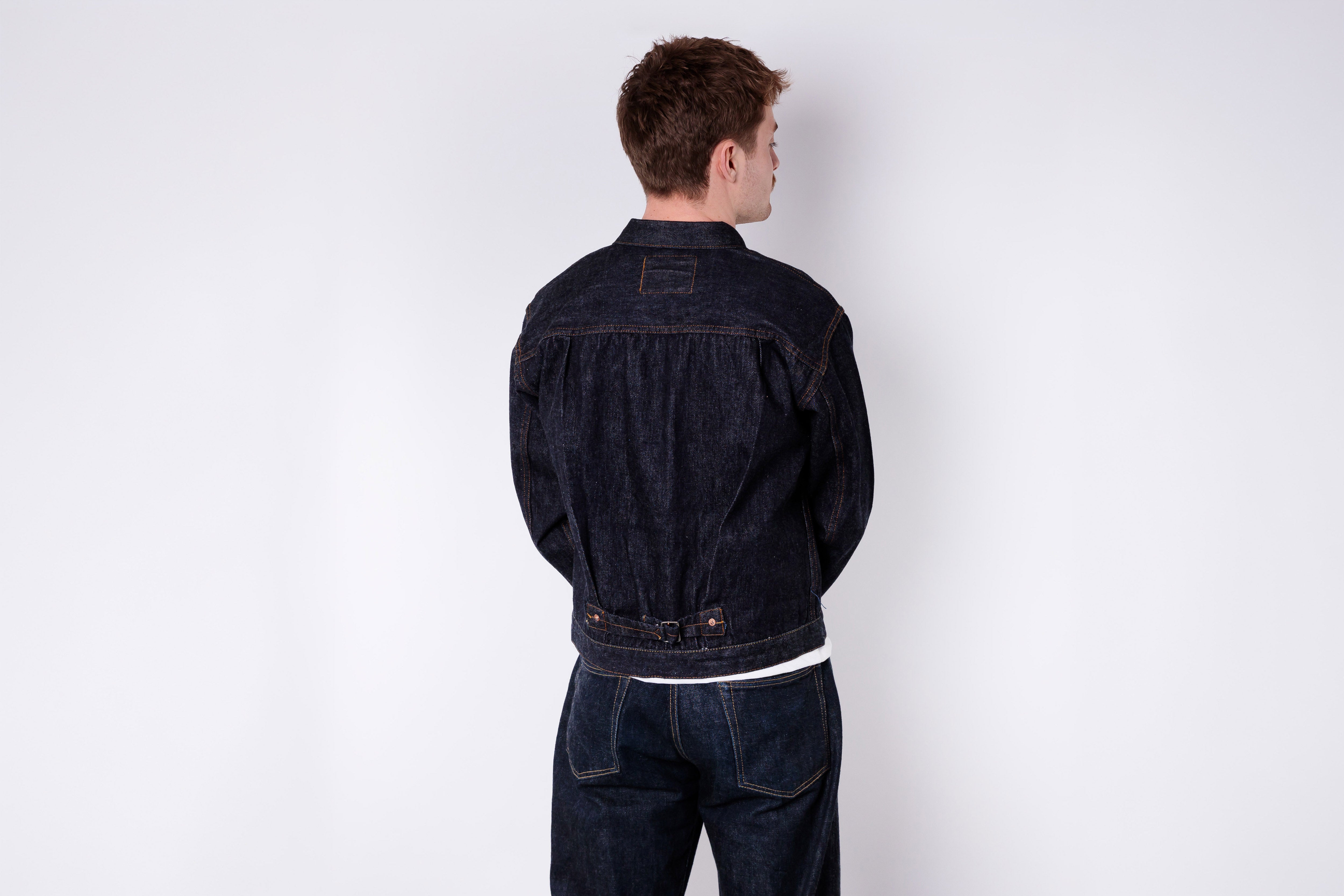 Person wearing a dark denim jacket on a white background
