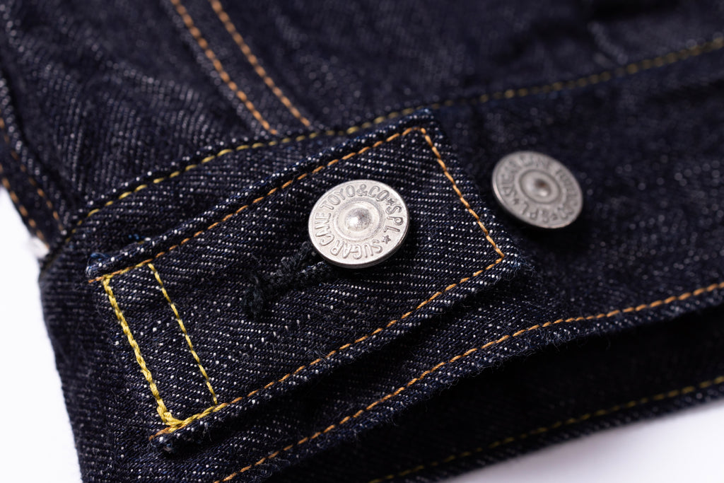 Close-up of a button on a denim fabric with a brand label.