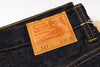 Close-up of dark indigo denim jeans showing the interior waistband and a prominent tan leather patch with the Sugar Creek 6 logo and text.