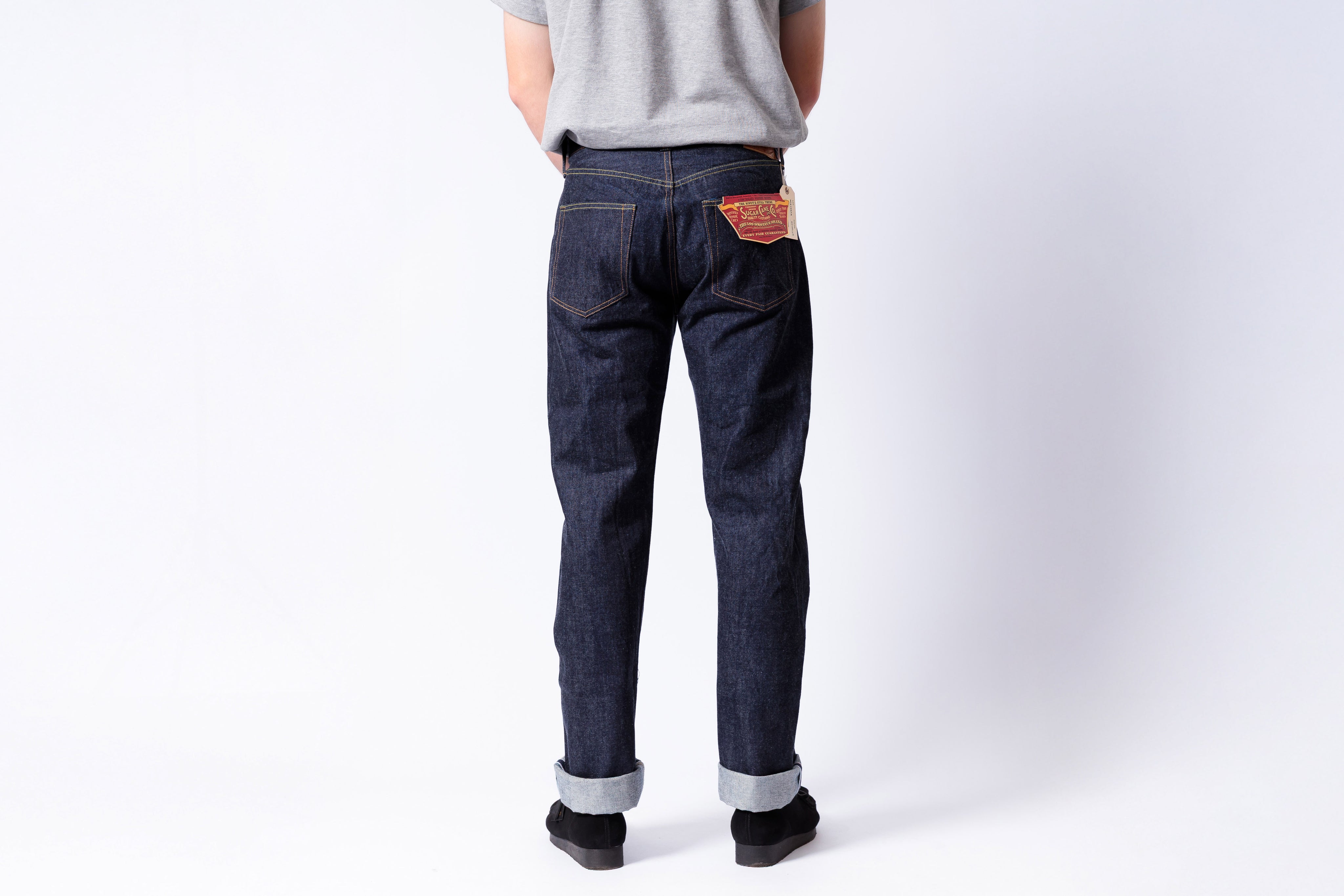 Person wearing dark blue jeans with a visible brand patch on a white background