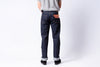 Person wearing dark blue jeans with a visible brand patch on a white background