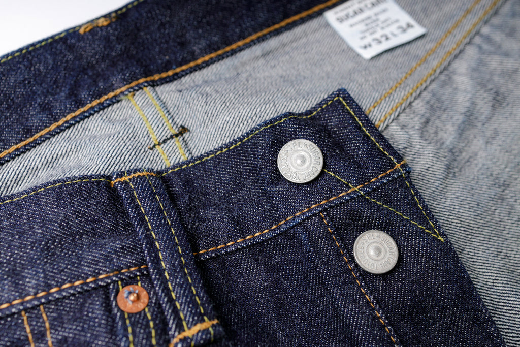 Close-up of a denim fabric with buttons and a label on a blurred background