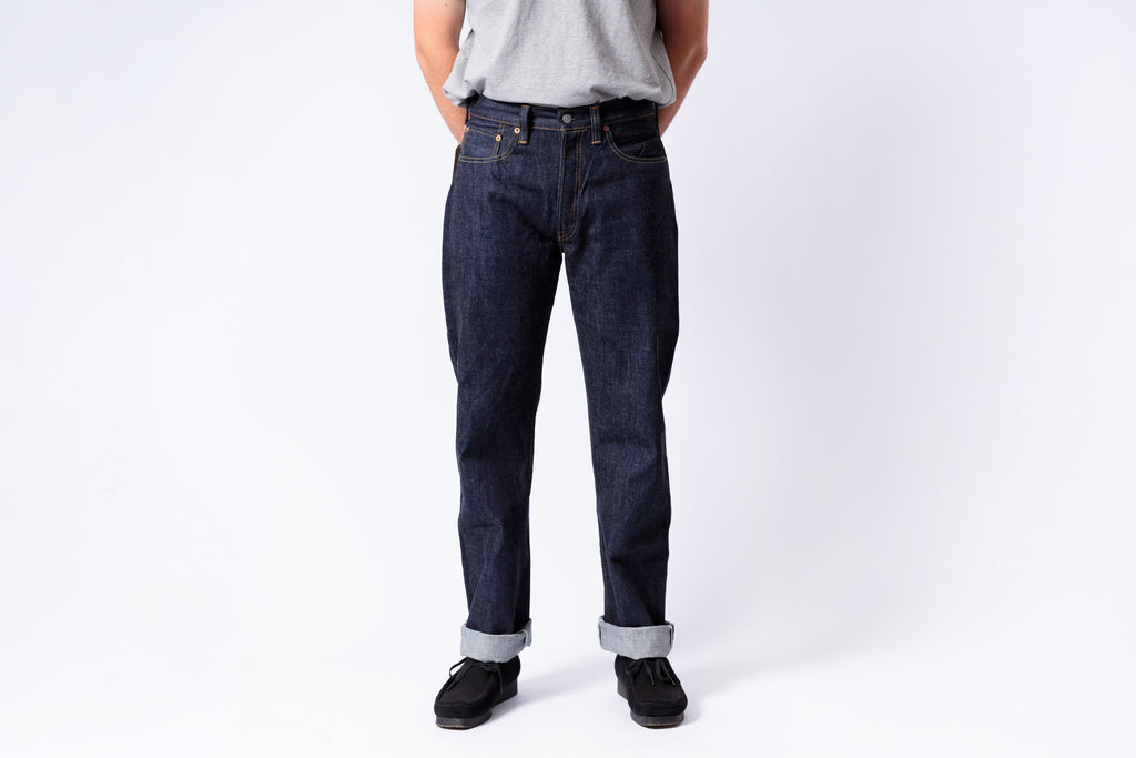 Person wearing dark blue jeans on a white background