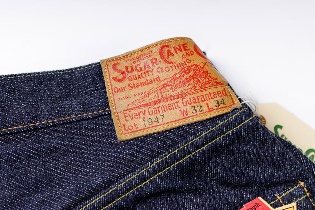 Close-up of a denim garment with a 'Sugar Cane' label on a white background