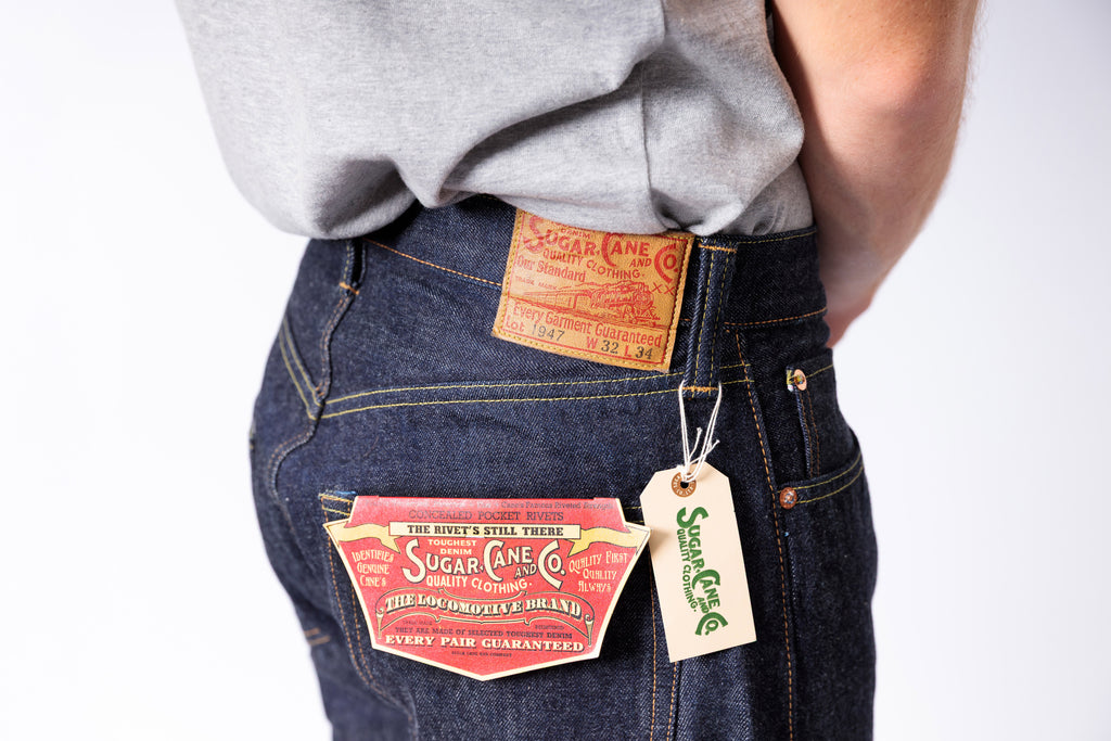 Person wearing blue jeans with brand labels on a white background