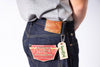 Person wearing blue jeans with brand labels on a white background