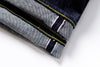 Close-up of folded denim fabric with yellow and white stitching on a white background