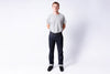Person wearing a plain gray t-shirt and dark jeans on a white background
