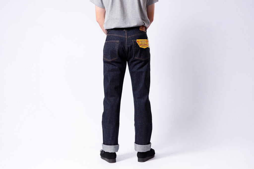 Person wearing dark blue jeans with a white background