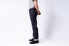 Person wearing dark blue jeans and black shoes on a white background