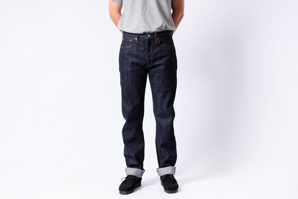 Person wearing dark blue jeans and a light gray shirt on a white background